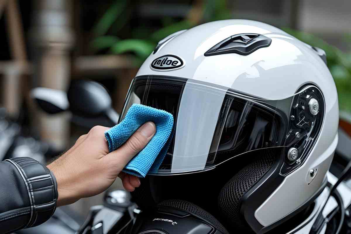 Una mano pulisce la visiera del casco