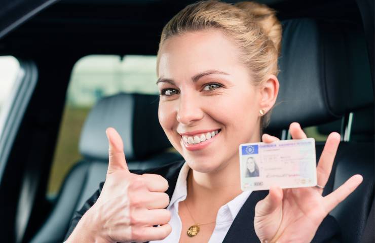 Una donna contenta che esibisce la patente