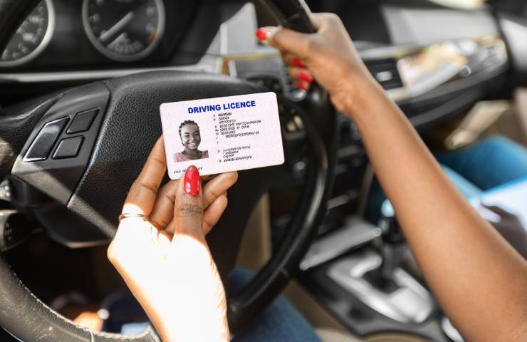 Una donna che tiene la patente in auto