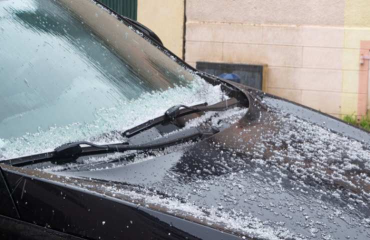 Un'auto con della grandine su cofano e parabrezza