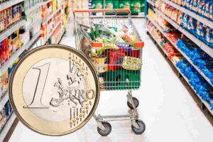 Un carrello della spesa pieno ed una moneta da 1 euro
