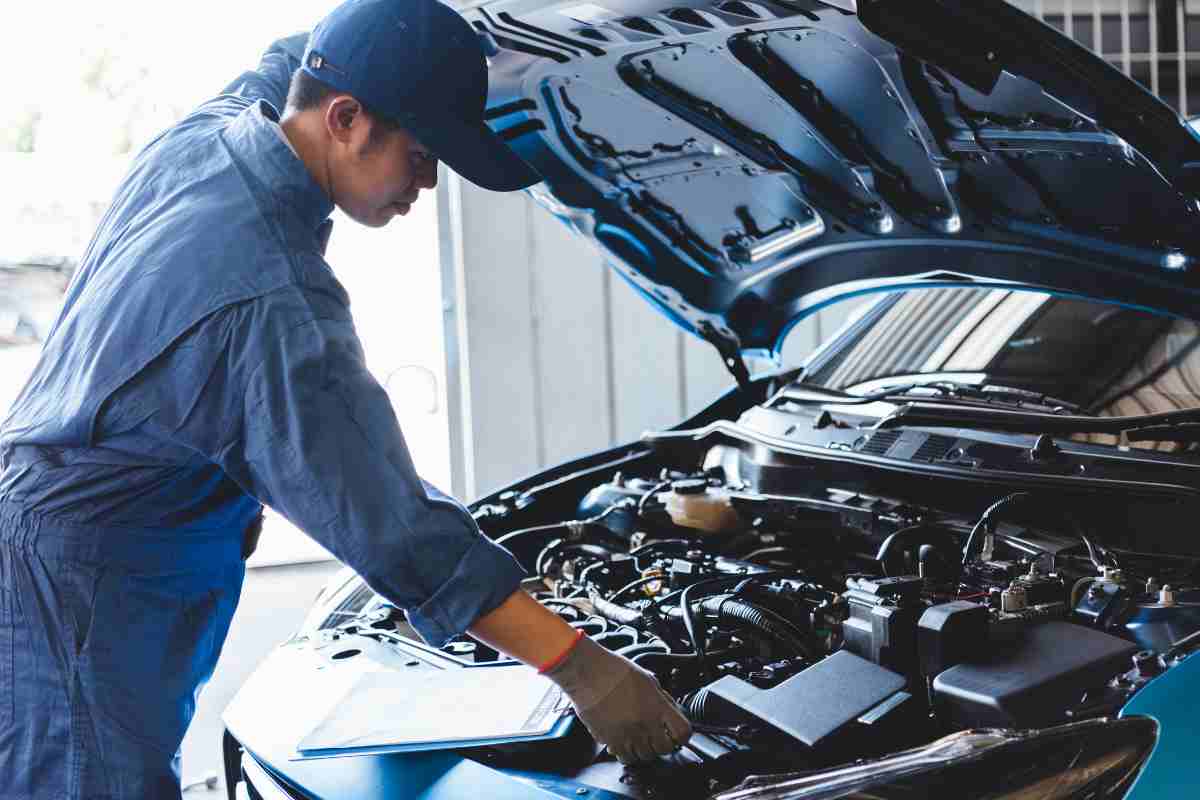 Un meccanico che controlla il motore di un'auto